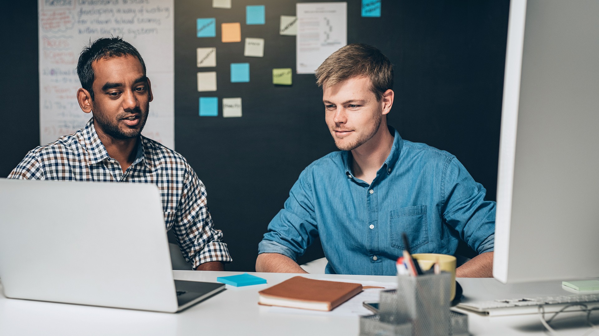 2 designers. Mastering Executive Coaching. Two Constructors look at the Camera.